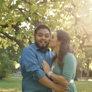 woman kissing man under the trees he looks surprised